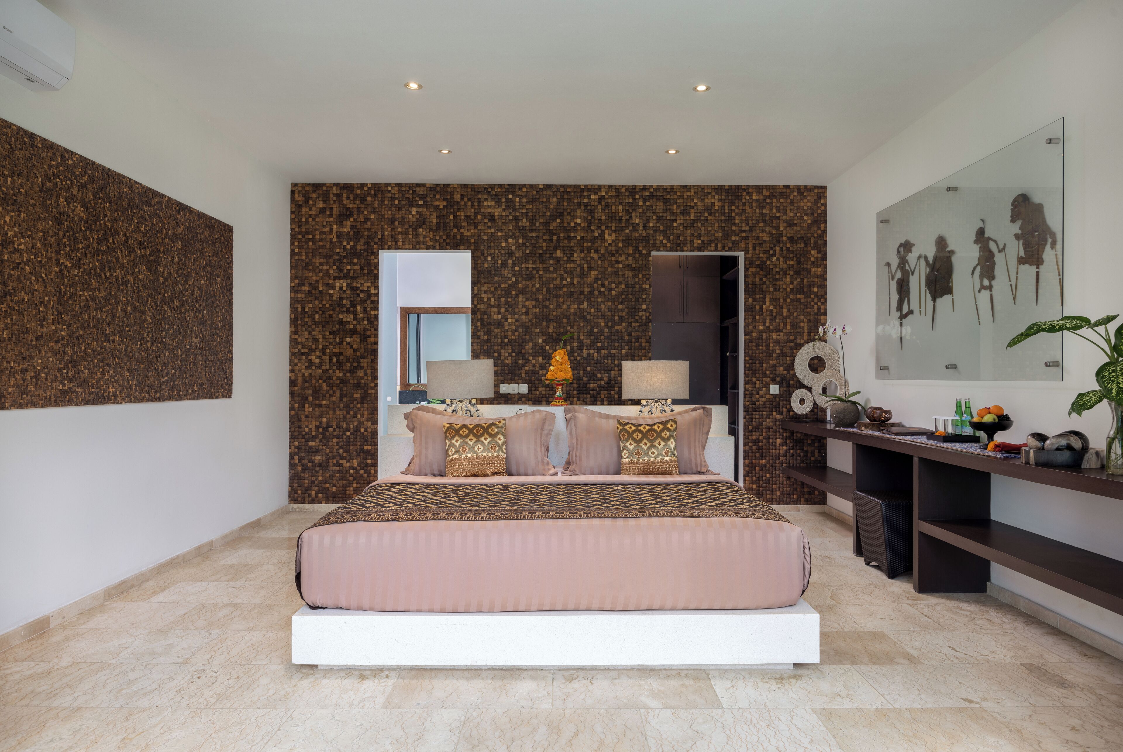 Un dormitorio moderno con una cama grande, un escritorio con computadora y un aire acondicionado instalado en la pared.
