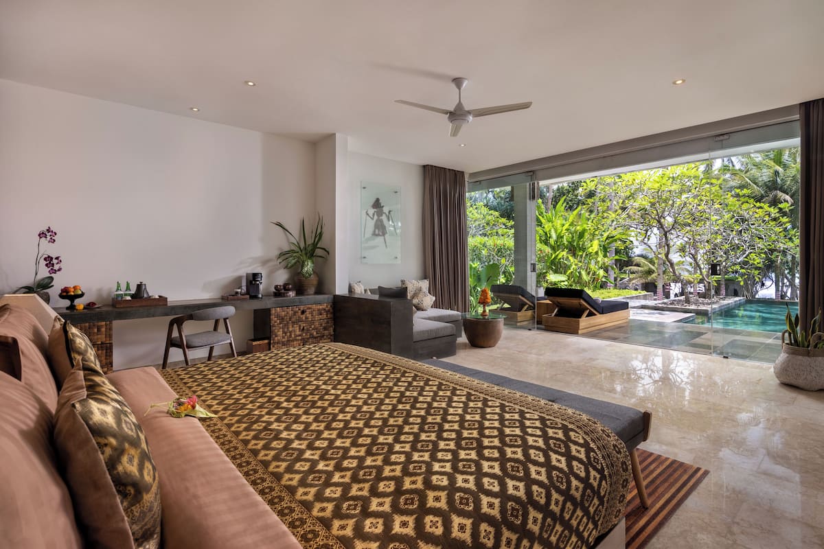 A modern bedroom with a large bed, a desk, and a view of a swimming pool.