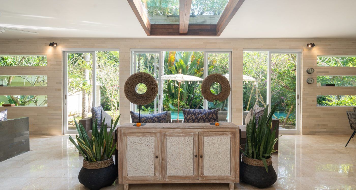 Una habitación amplia con un gran ventanal, un armario de madera y dos plantas en macetas.
