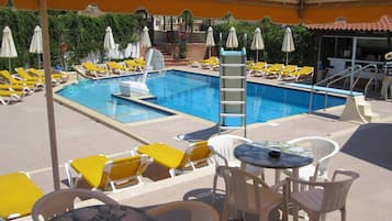 Una piscina al aire libre, sombrillas, sillones reclinables de piscina