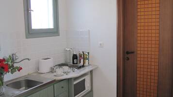 A kitchen with a sink, a window, a door, and a countertop with a bottle and a box.