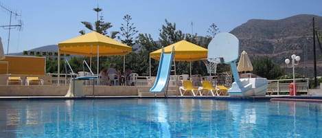 Una piscina al aire libre, sombrillas, sillones reclinables de piscina