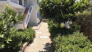 A pathway leading to a white building with blue accents and a staircase.
