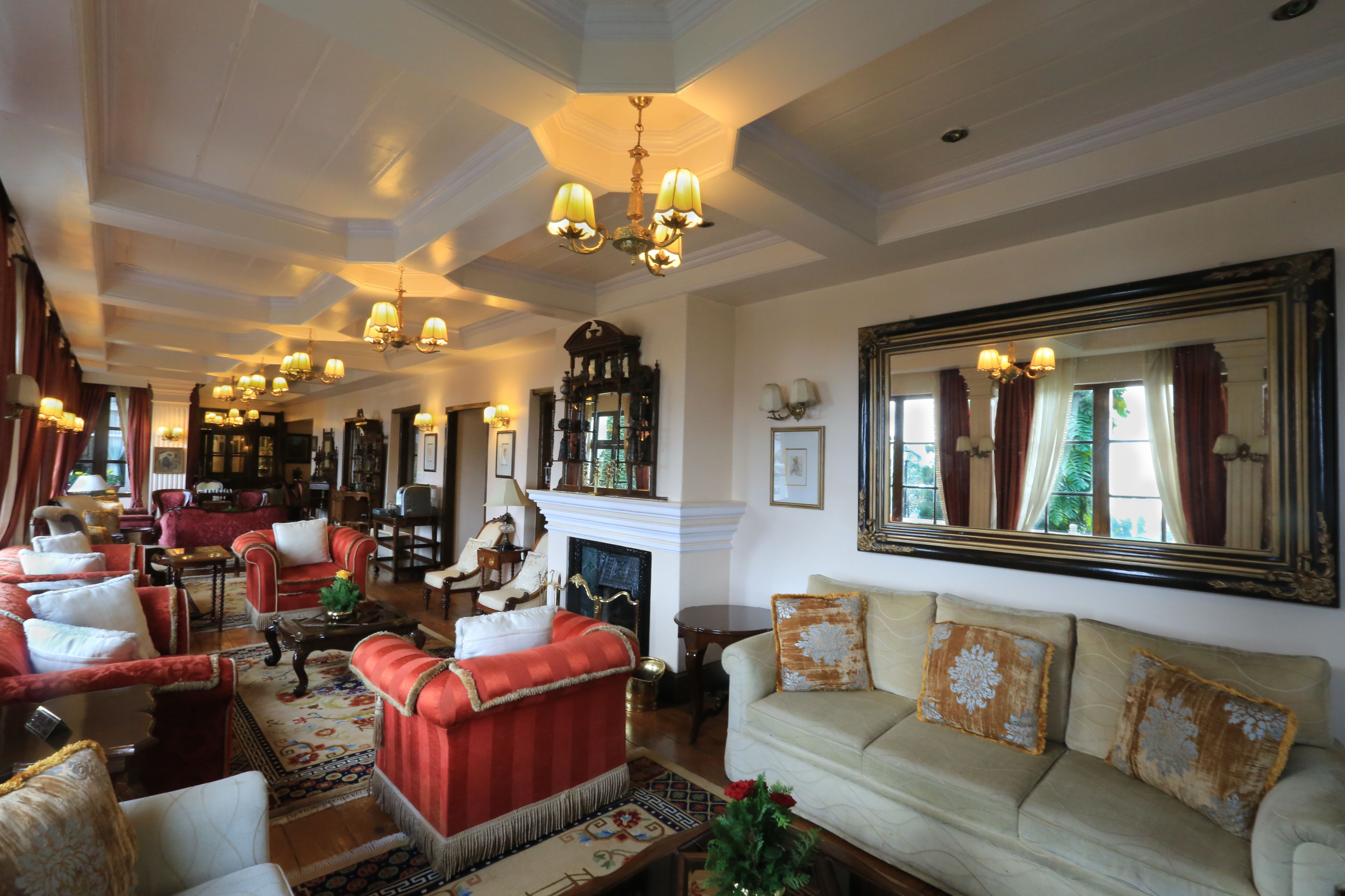 A spacious living room with a fireplace, multiple seating areas, and a large mirror.