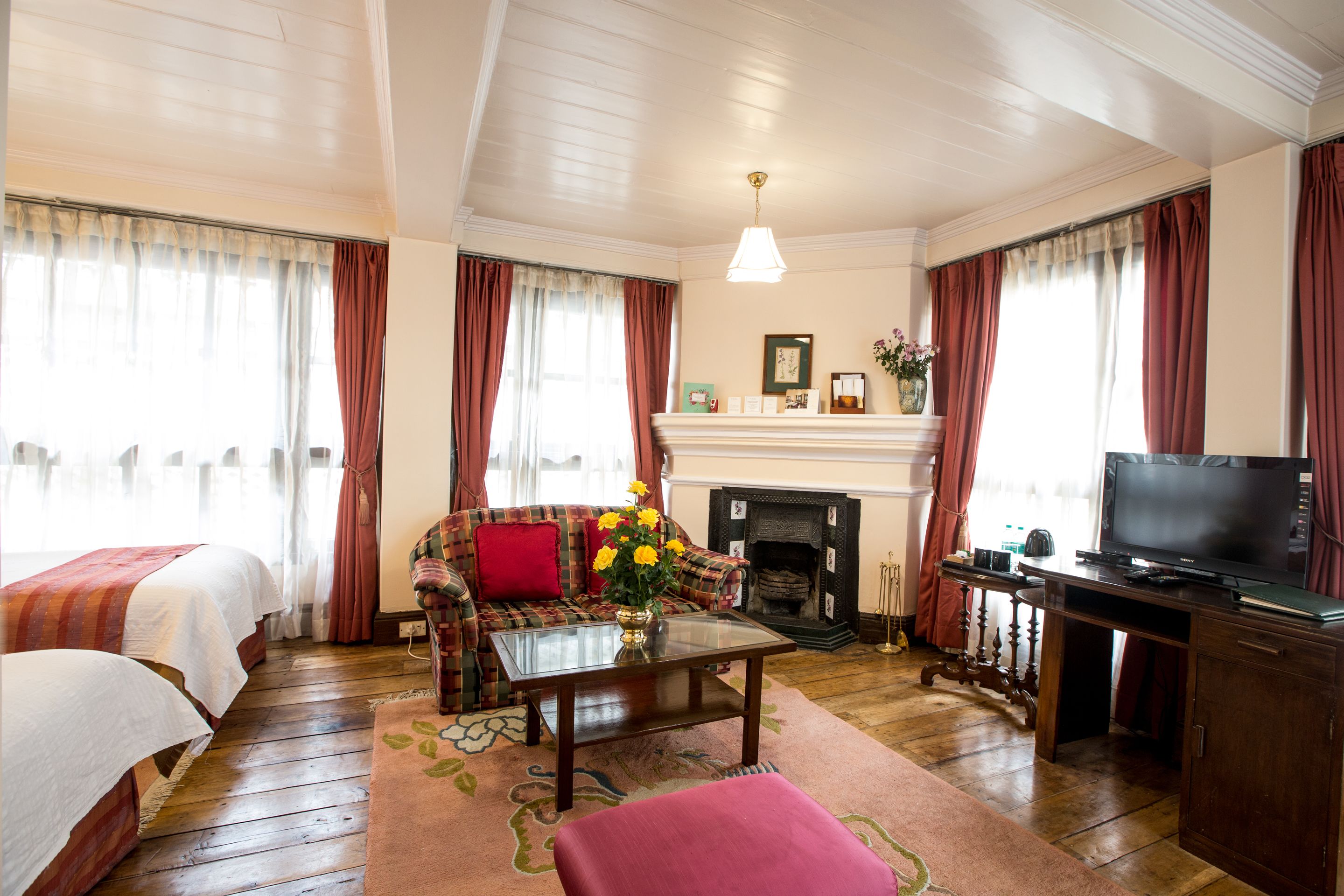 A hotel room with a sofa, two beds, a television, a fireplace, and a coffee table.
