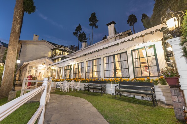 A well-lit building with a pathway leading to a seating area with benches and chairs. - The Elgin, Darjeeling (Darjeeling)