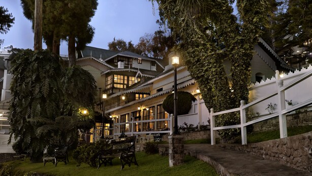 Un edificio grande de varios pisos con un estilo arquitectónico tradicional, que cuenta con un balcón con barandilla y una escalera de piedra que conduce a él.