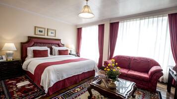 Ein Hotelzimmer mit einem großen Bett, einem roten Sofa, einem Glastisch und einem dekorativen Teppich.