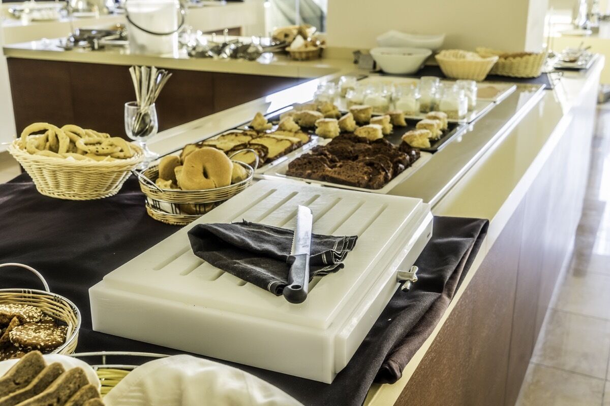 Montaje de buffet con diversos alimentos y un cuchillo sobre una bandeja blanca.