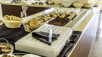 Montaje de buffet con diversos alimentos y un cuchillo sobre una bandeja blanca.