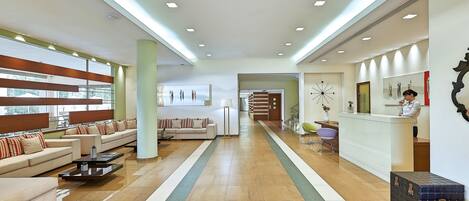 A spacious lobby with a reception desk, sofas, and a coffee table.