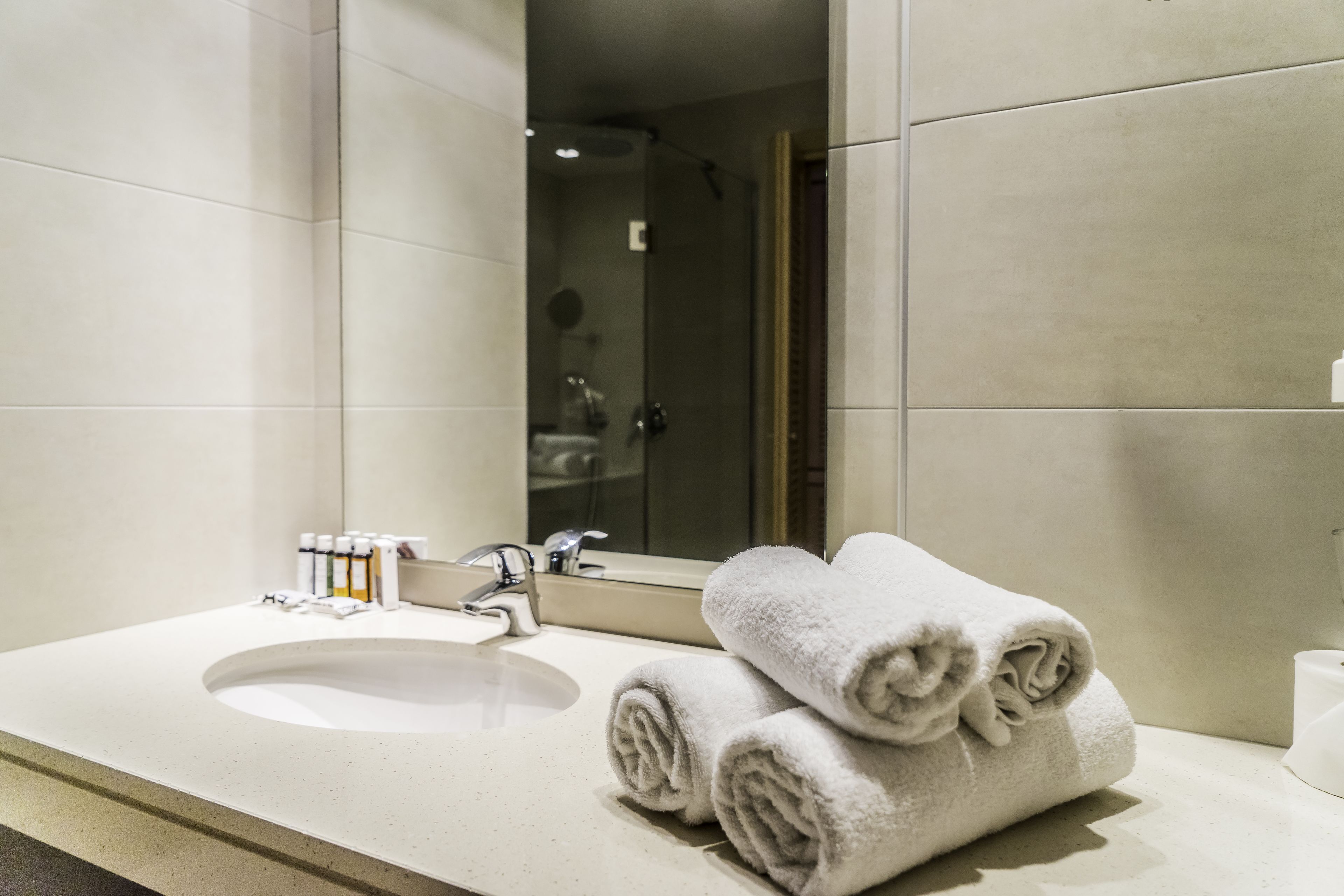 A bathroom with a sink, mirror, and towels.