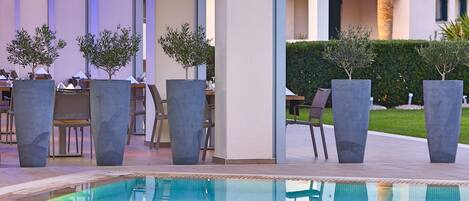 A poolside area with modern seating and potted plants.