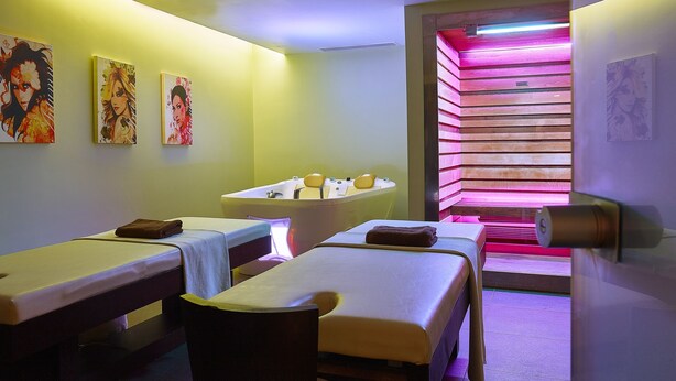 A spa room with two massage tables, a large bathtub, and wall art. - Castello Boutique Resort & Spa - Adults Only (Agios Nikolaos)