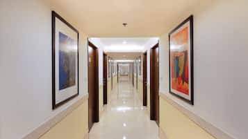 A long, well-lit hallway with framed artwork on the walls, leading to multiple doors.