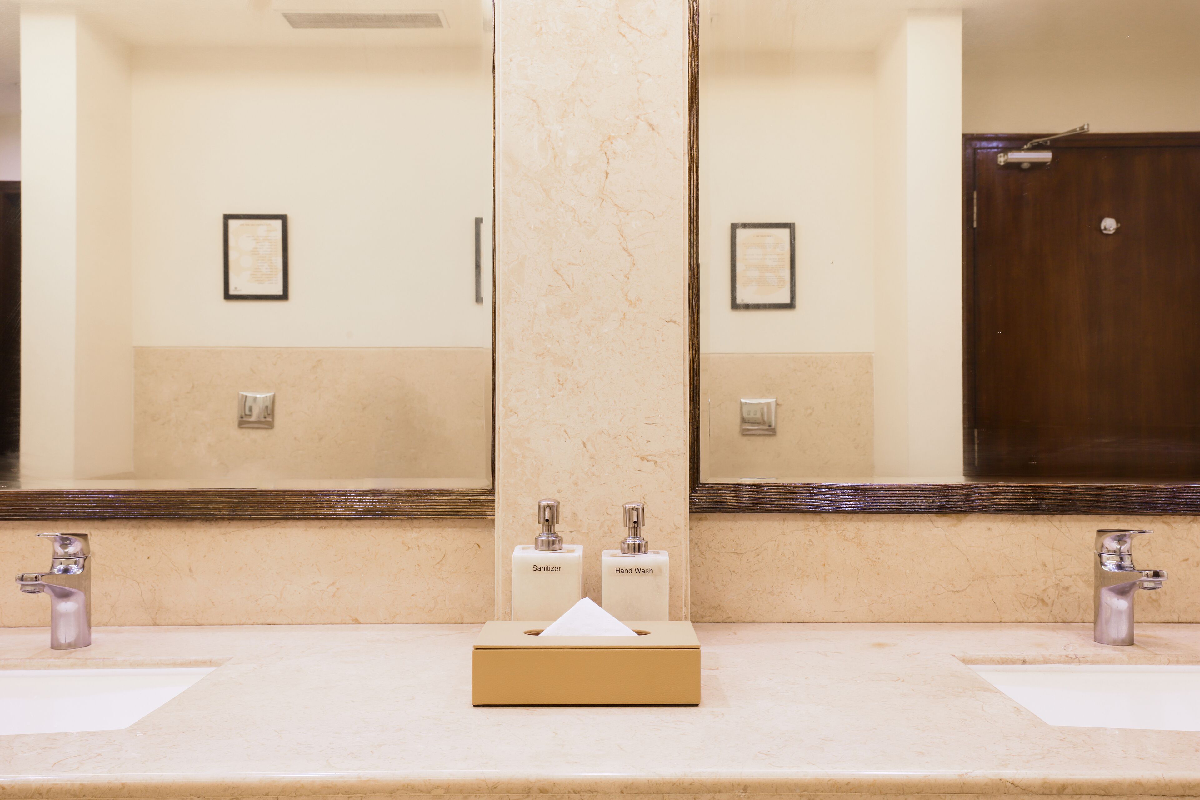 Une salle de bain avec deux lavabos, un miroir et une boîte de mouchoirs.