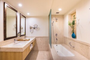 Un baño moderno con un espejo grande, dos lavamanos, una bañera y una ducha.