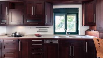 Una cocina moderna con armarios de madera oscura, lavavajillas integrado y ventana con vista a la vegetación.