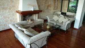 Ein Wohnzimmer mit Steinsäule, Kamin, zwei Sofas, einem Couchtisch und einem Glastisch.