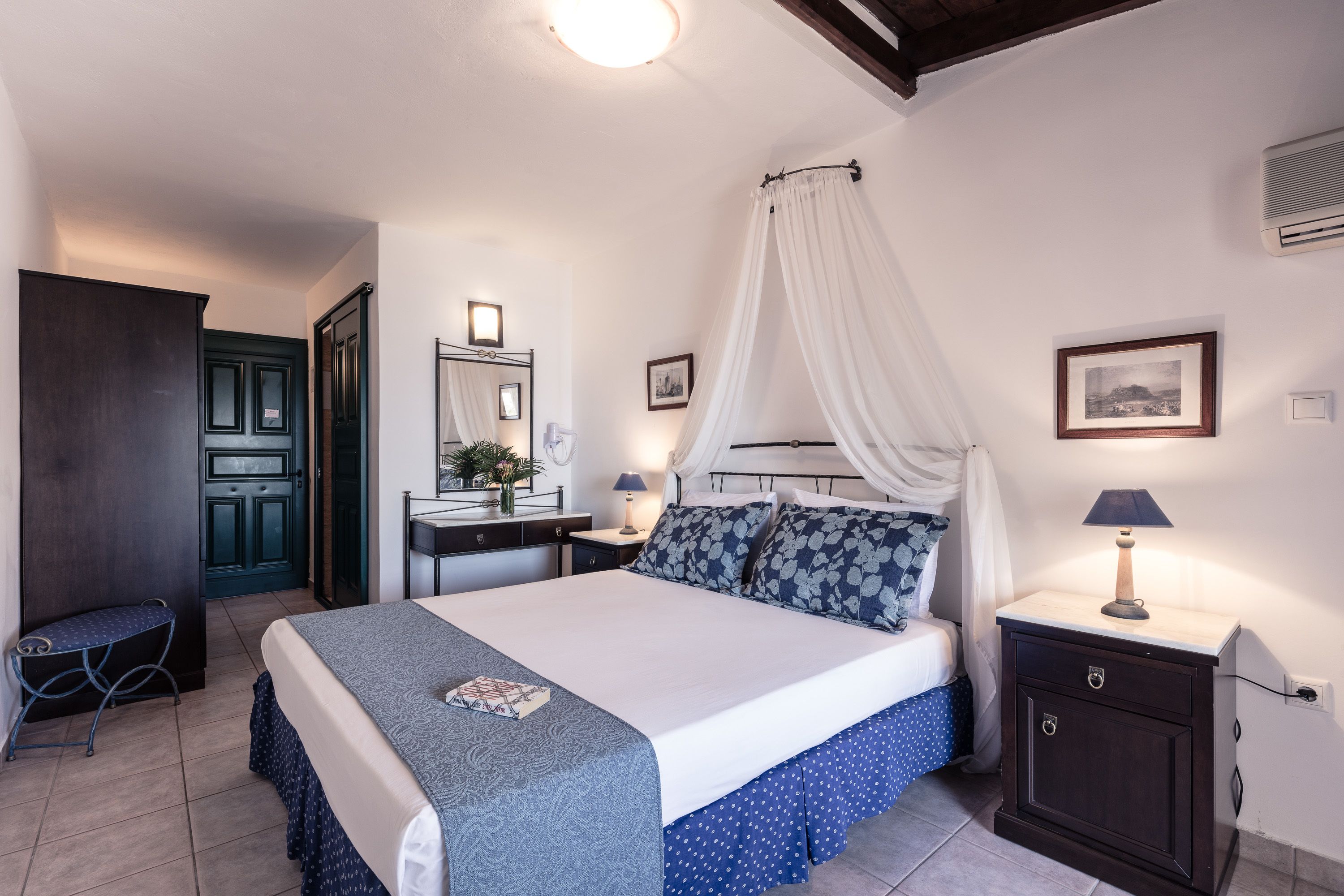 A bedroom with a bed, bedside table, nightstand, and a small desk with a chair.