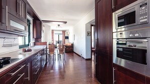 Eine moderne Küche mit dunklen Holzschränken, Edelstahlgeräten und einer zentralen Kochinsel mit Stühlen.