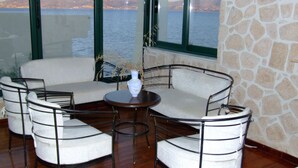 Eine Sitzecke mit einer Couch und Sesseln, ein kleiner Tisch mit einer Vase und Meerblick durch große Fenster.