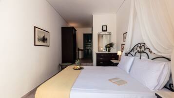 Una camera da letto ordinata con un letto, un comodino con una lampada, uno specchio e un quadro appeso al muro.