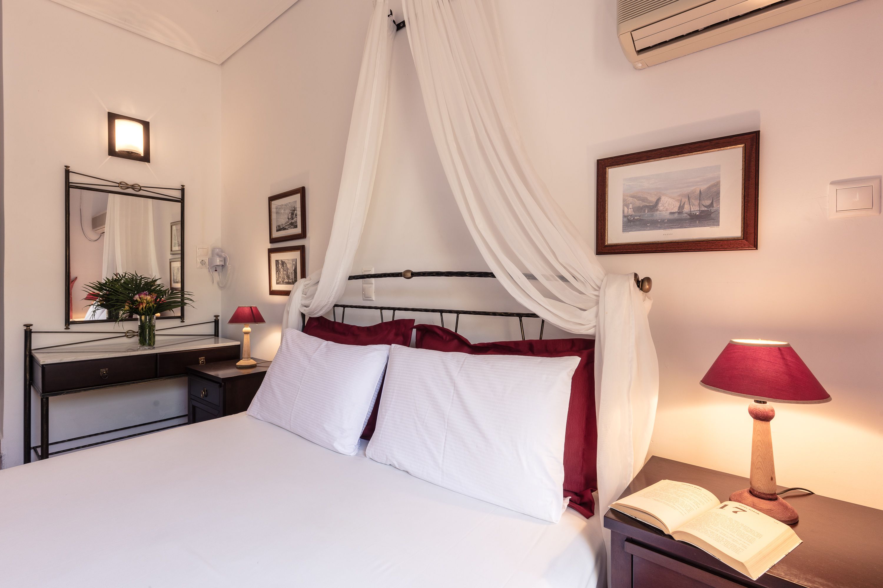 A neatly arranged bedroom with a bed, bedside table, lamp, and a mirror.