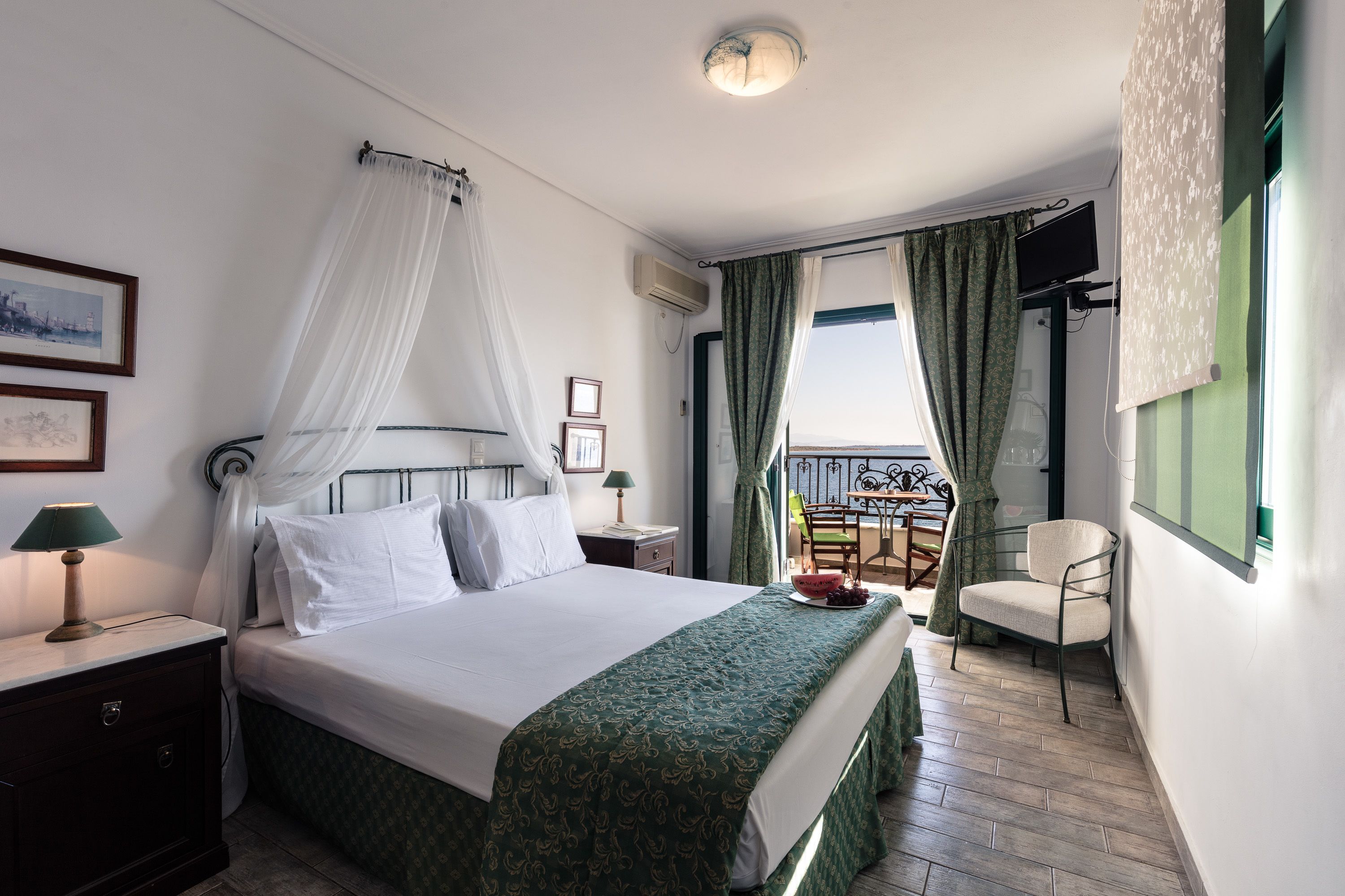 Una habitación de hotel con cama, mesita de noche, una silla, un balcón con vistas y televisión.