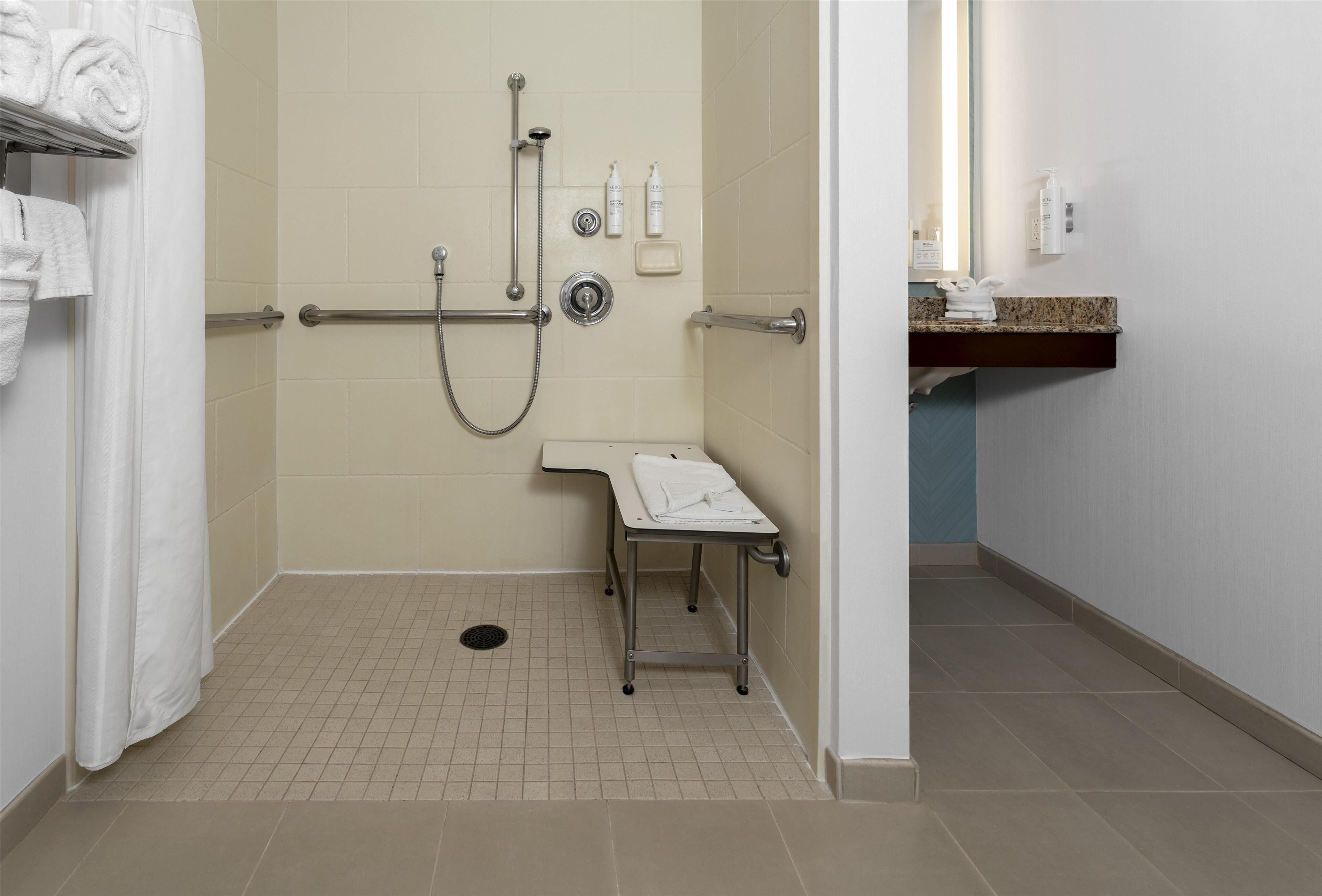 A handicap-accessible shower area with grab bars, a bench, and a towel rack.