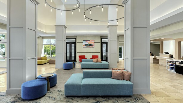 A spacious lobby with a high ceiling, modern lighting fixtures, and seating areas. - Hilton Garden Inn Eugene/Springfield (Springfield)