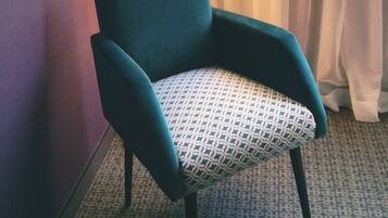 Un sillón color turquesa con un cojín estampado en una habitación de hotel.