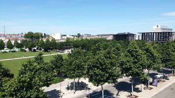 A park with a green field, trees, and a building in the background.