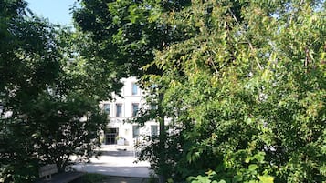 A hotel with a central entrance, surrounded by lush greenery and a bench.