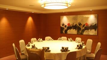 A conference room with a round table, chairs, and a painting on the wall.