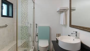 A modern bathroom with a glass-enclosed shower, a white toilet, a large sink with a mirror, and a tiled shower area.