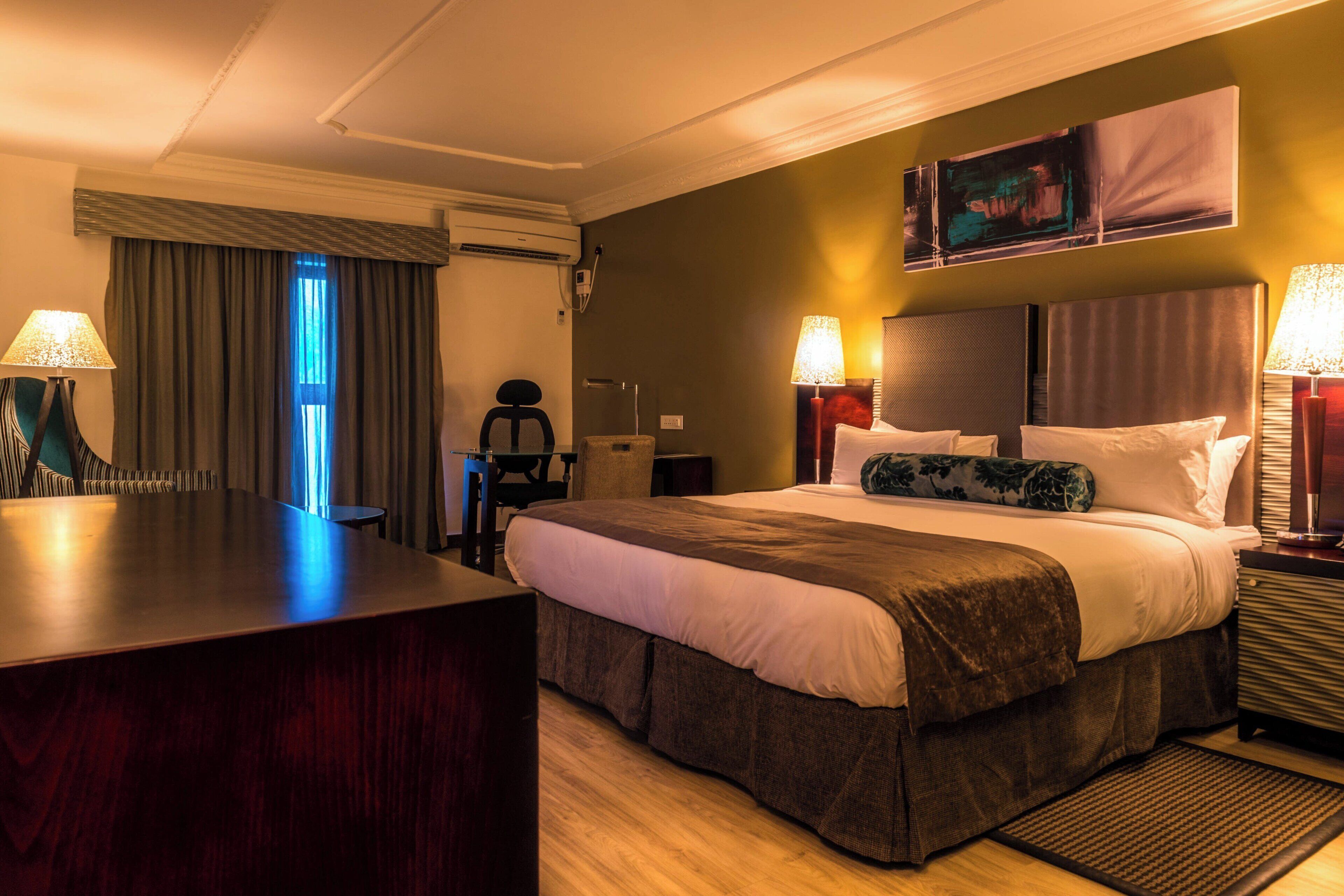 Een hotelkamer met een groot bed, twee bedlampen, een bureau en een stoel.