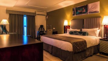 Een hotelkamer met een groot bed, twee bedlampen, een bureau en een stoel.