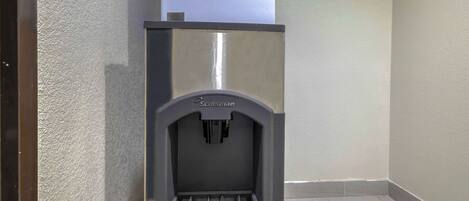 A compact, modern water dispenser branded 'Scotsman' in a corner of a room with a tiled floor and plain walls.