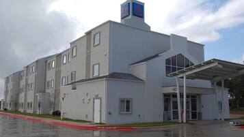 A modern multi-story building with a flat roof, large windows, and a covered entrance area.