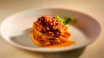 Un plato de pasta con salsa de tomate y un adorno de hojas verdes.