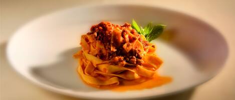 Un plato de pasta con salsa de tomate y un adorno de hojas verdes.