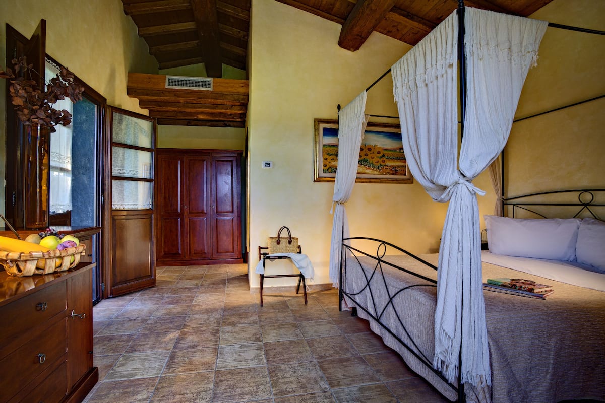 A bedroom with a bed, a bedside table, a wooden wardrobe, and a window with curtains.
