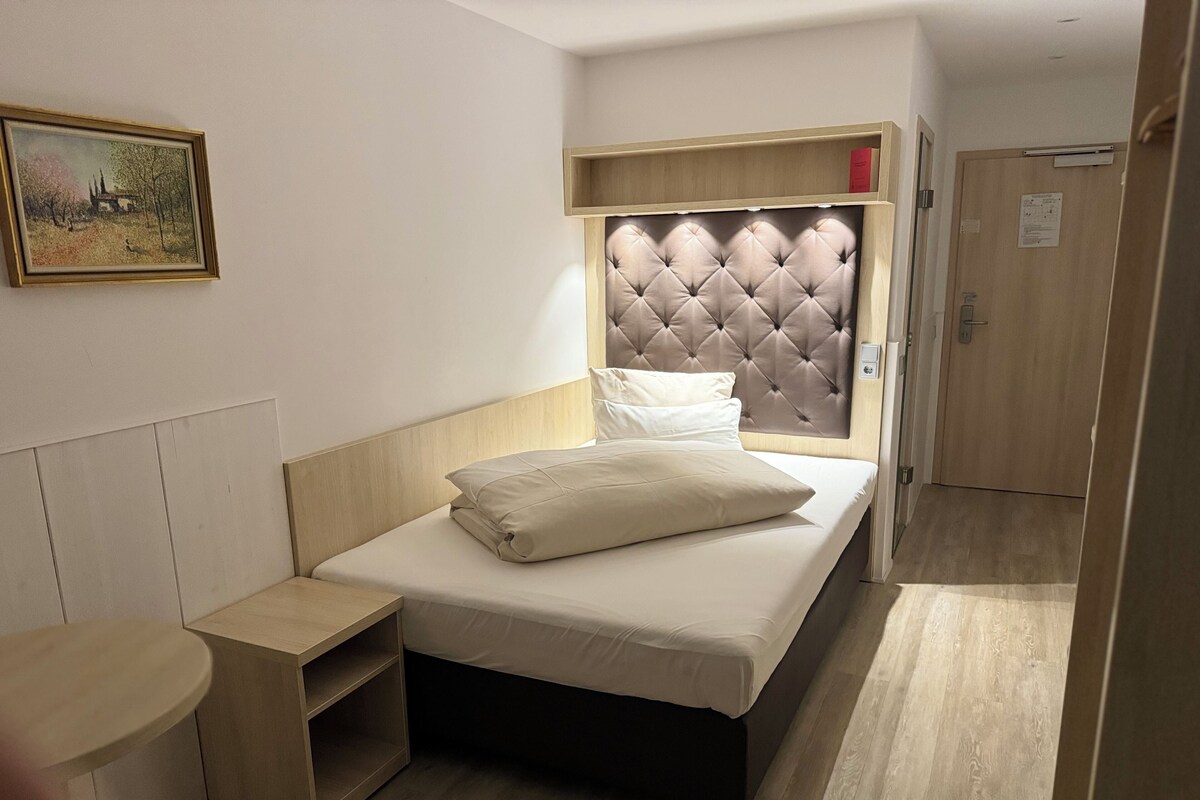 Un dormitorio con cama, mesita de noche y cabecera con iluminación integrada.