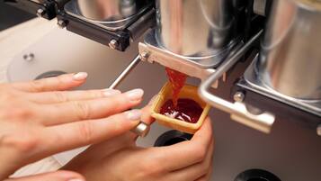 A person pouring a red liquid into a small container.