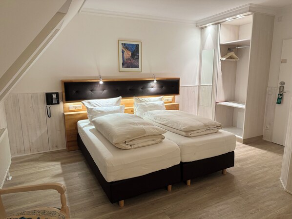A bedroom with a bed, bedside tables, a telephone, a painting, and a wardrobe. - Hotel Haase (Laatzen)