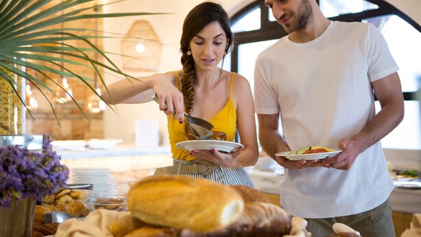 A buffet setup with various food items and a couple standing nearby.