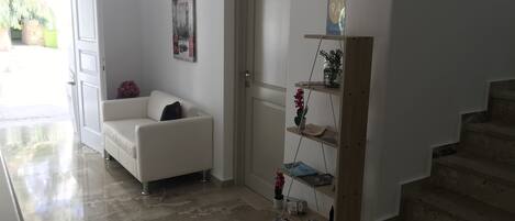 Ein modernes Wohnzimmer mit einem weißen Sofa, einer Tür, einem Bücherregal und einer Treppe.