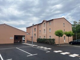 Un edificio residencial de varios pisos con un estacionamiento al frente.