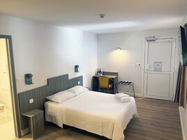 Habitación de hotel con cama, mesita de noche, silla, escritorio y armario.